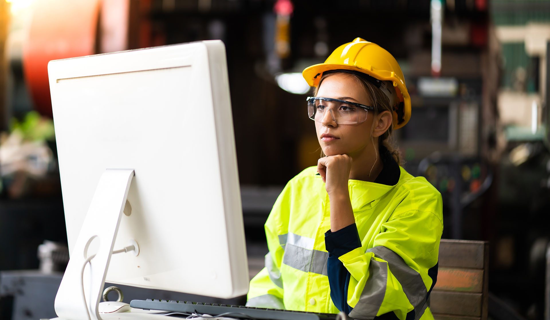 A woman in a hard hat reviews training materials on a computer.
