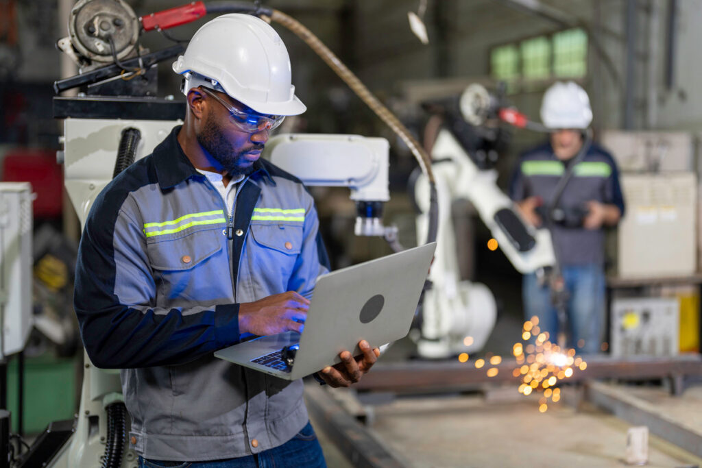 A worker browses training content on a laptop from the shop floor.