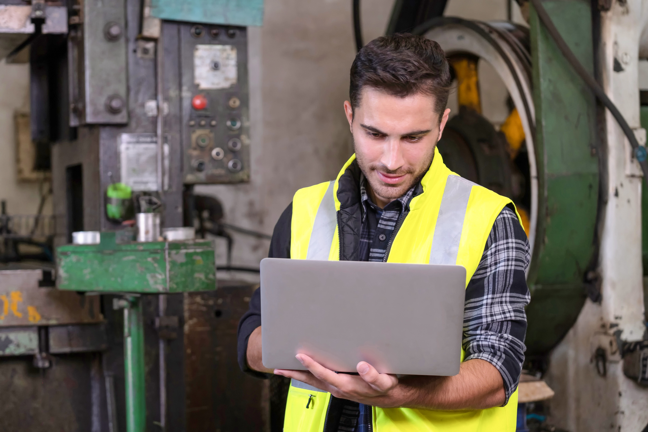 An employee in a safety vest looks up microlearning training content on a laptop.