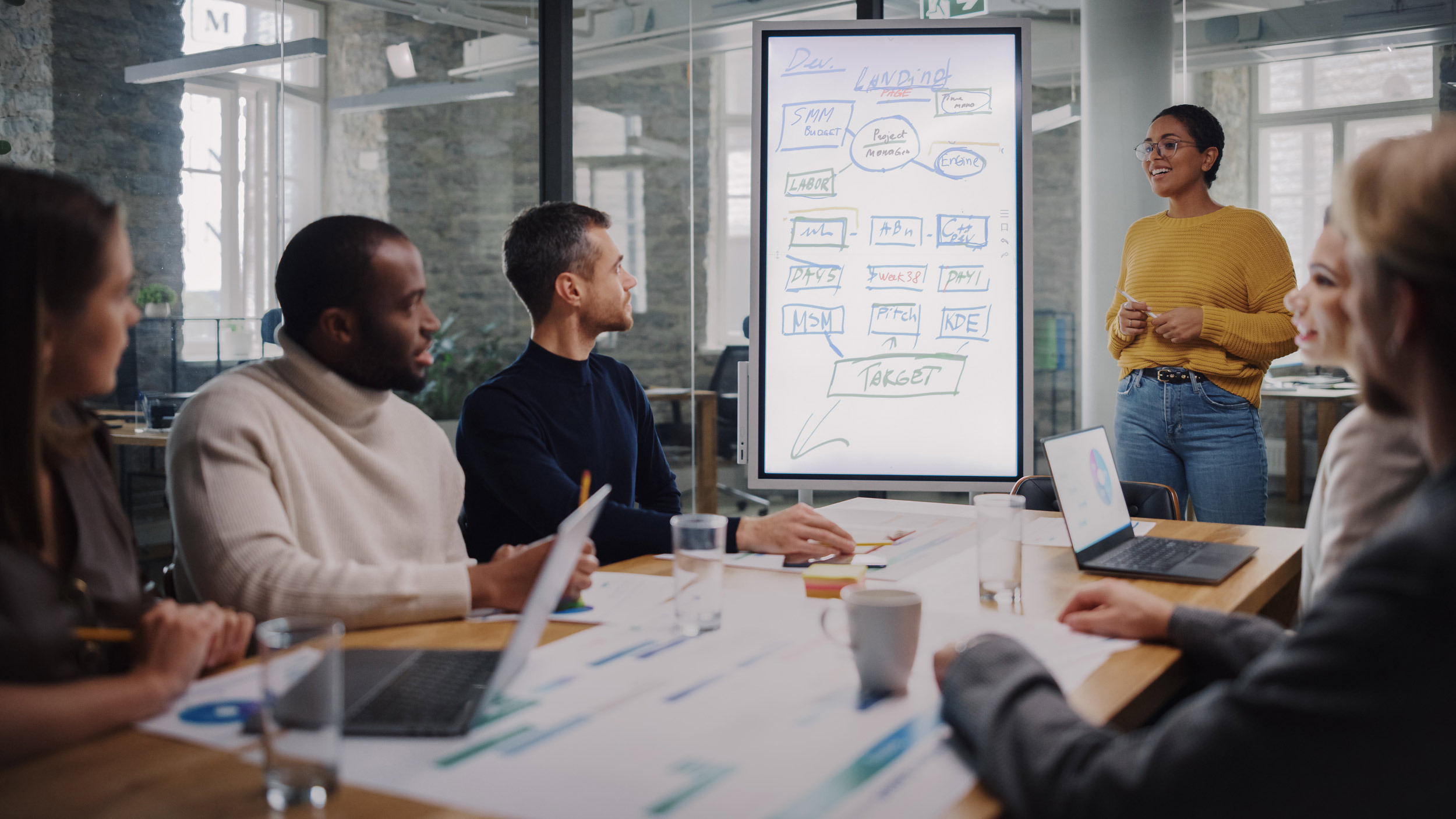 Coworkers around a table review a workflow from a project manager.